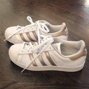 White Adidas Superstars with rose gold stripes